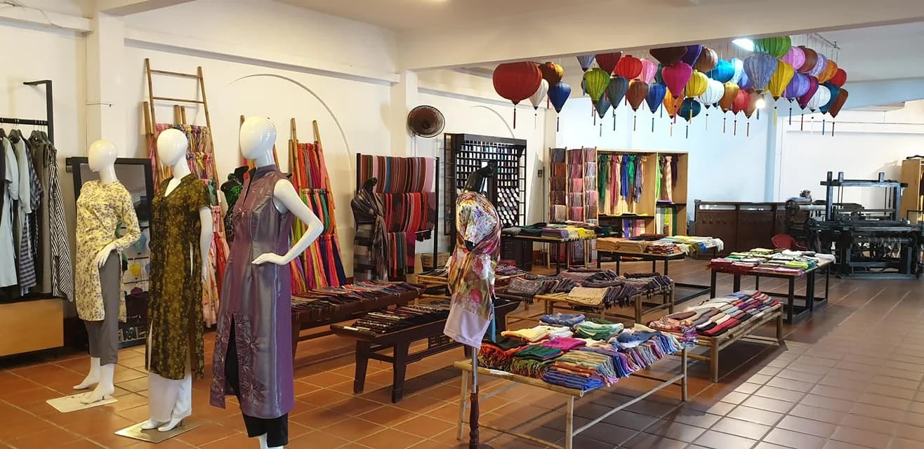 Skilled tailors measuring and sewing custom silk clothing in a local shop in Hoi An, the tailoring capital of Vietnam