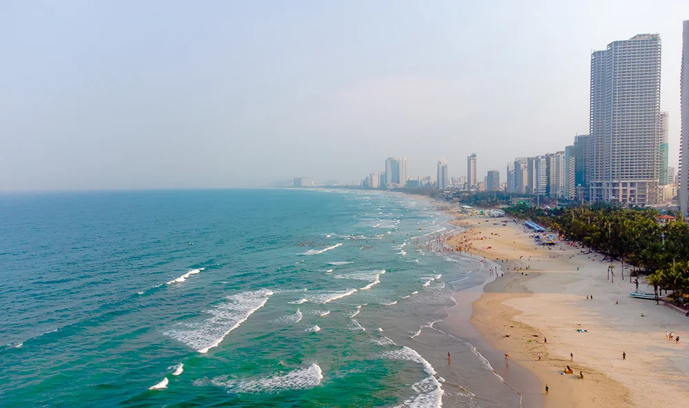 Aerial view of the long white sandy coastline and blue waters of My Khe Beach in Da Nang.