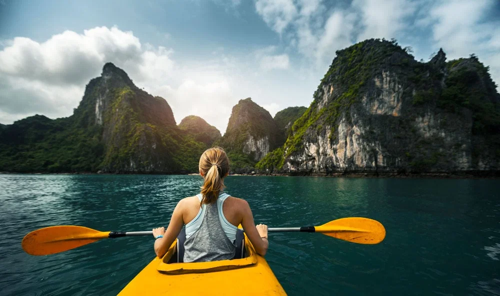 Small wooden cruise boats and colorful kayaks in the calm turquoise water of Lan Ha Ba