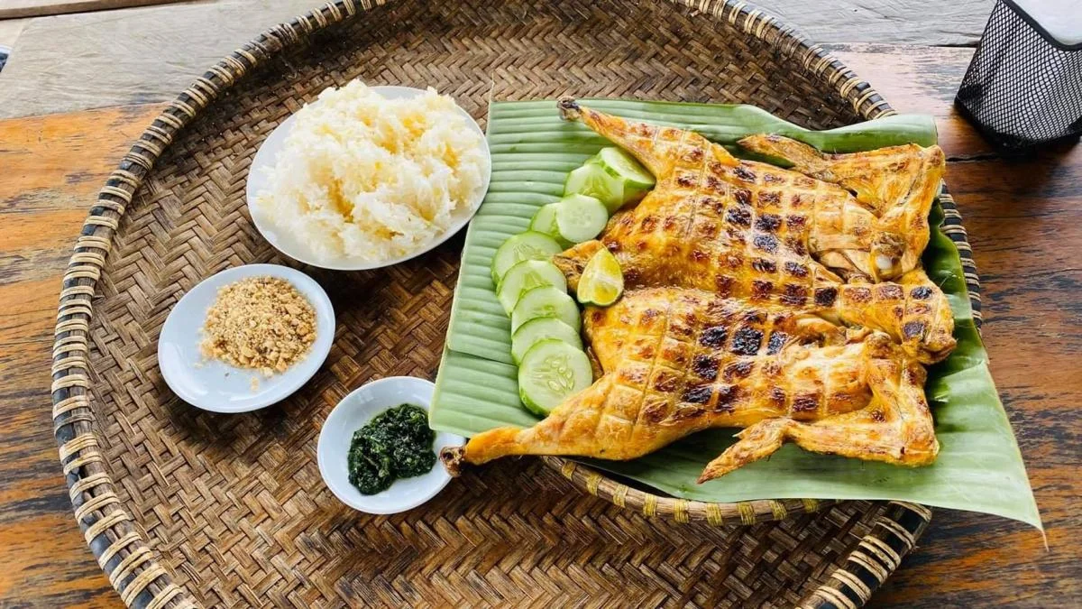 Golden grilled chicken served on banana leaves with a bowl of green Cheo salt in rural Phong Nha.