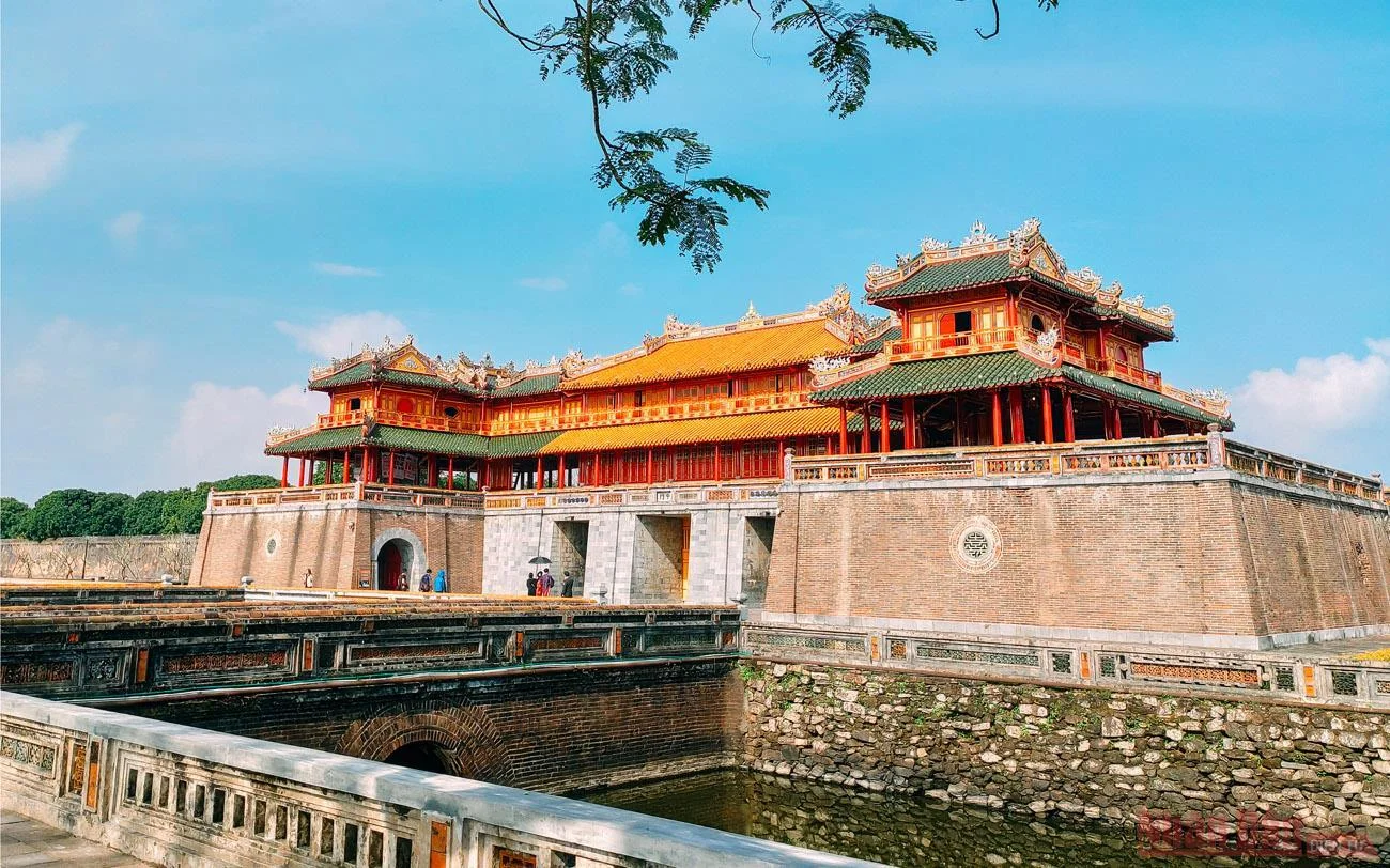 The main entrance of the Hue Imperial Citadel glowing in warm yellow tones at dusk