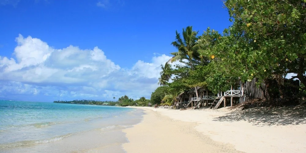 The relaxing scenery of An Bang Beach in Hoi An with white sand, blue water, and rustic beach umbrellas.