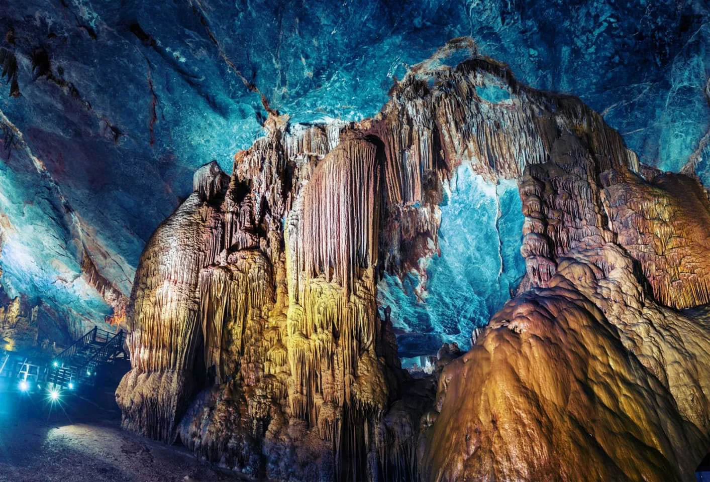 Illuminated limestone formations and elevated wooden walkways inside Paradise Cave, Phong Nha.