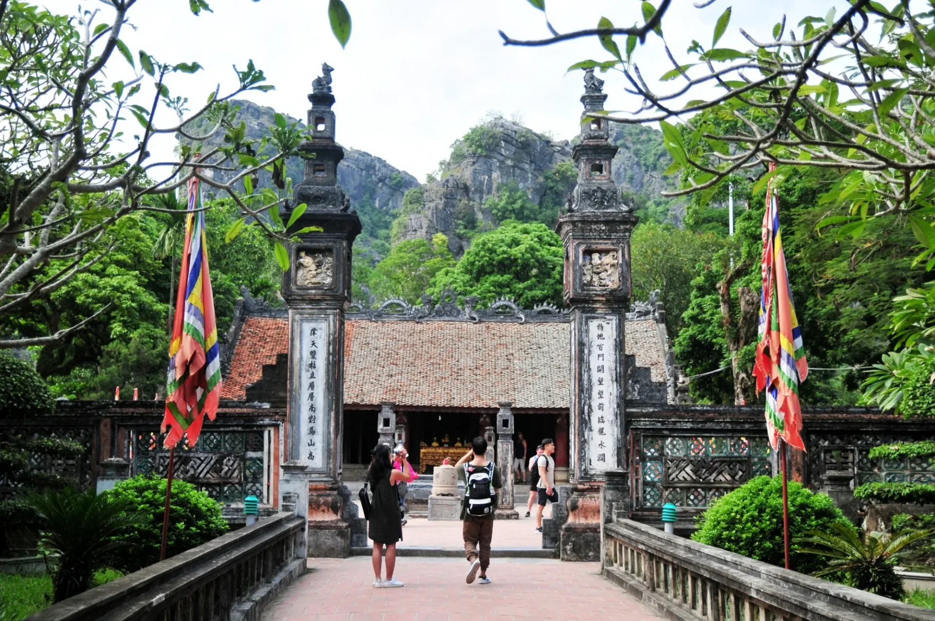 Traditional stone-and-wood architecture of Dinh King Temple surrounded by karst mountains in Hoa Lu, Ninh Binh.