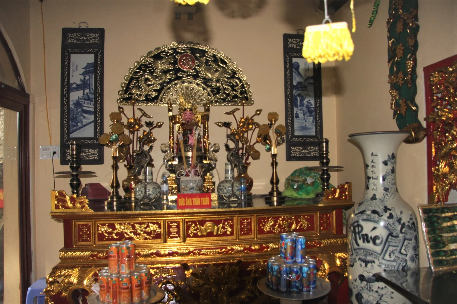 A traditional Vietnamese temple with red roofs tucked against a massive limestone mountain on Cat Ba Island.