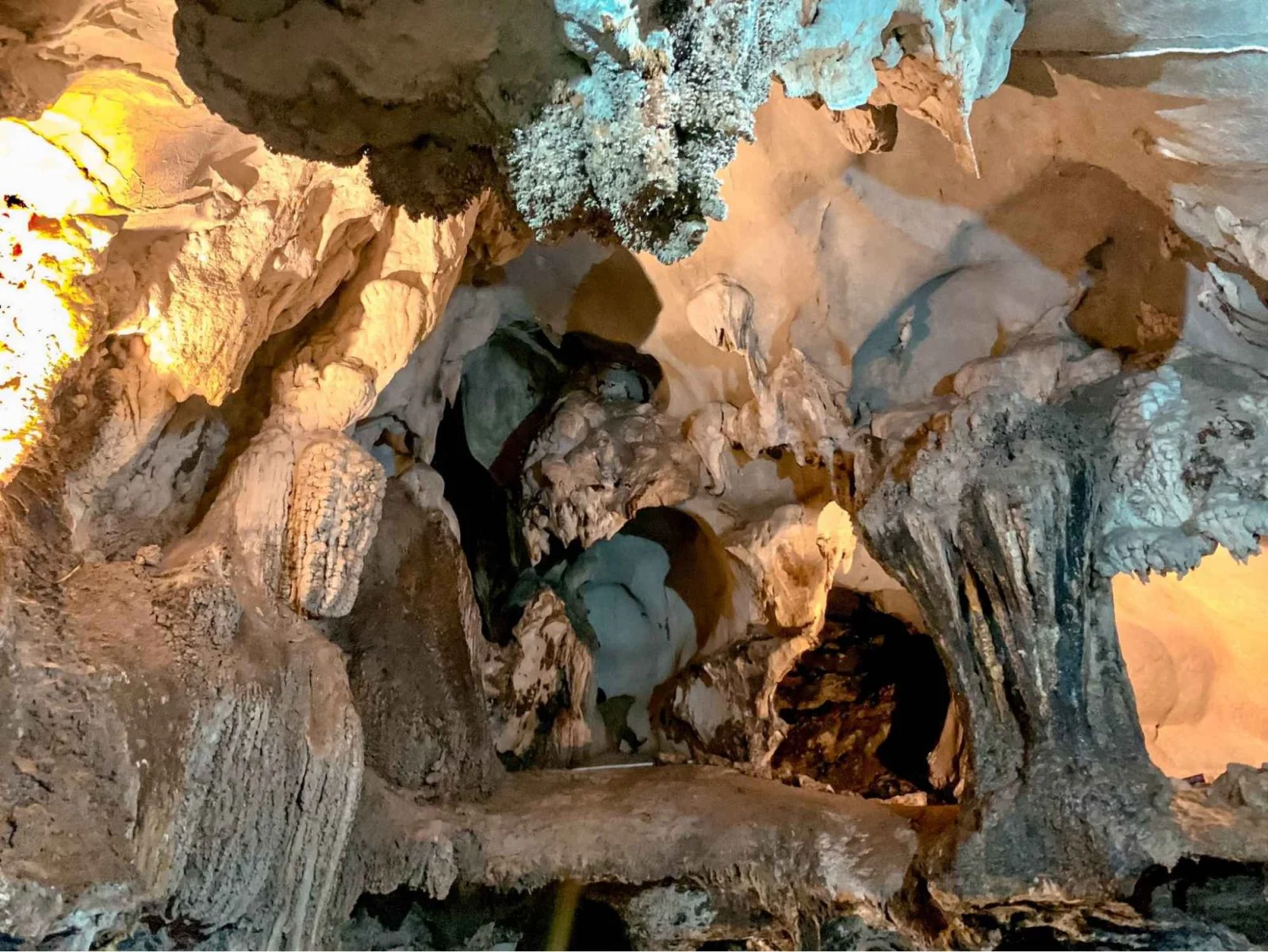 A well-lit interior of Trung Trang Cave showing sharp, sparkling limestone formations hanging from the ceiling.