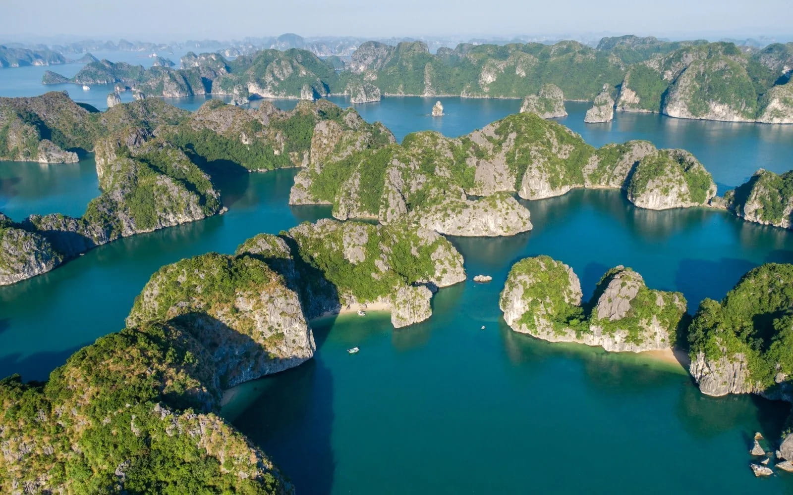 Two travelers in a yellow kayak paddling through a calm, enclosed lagoon in Lan Ha Bay.