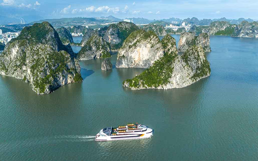 A premium cruise ship sailing between the limestone mountains of Ha Long and Lan Ha Bay.